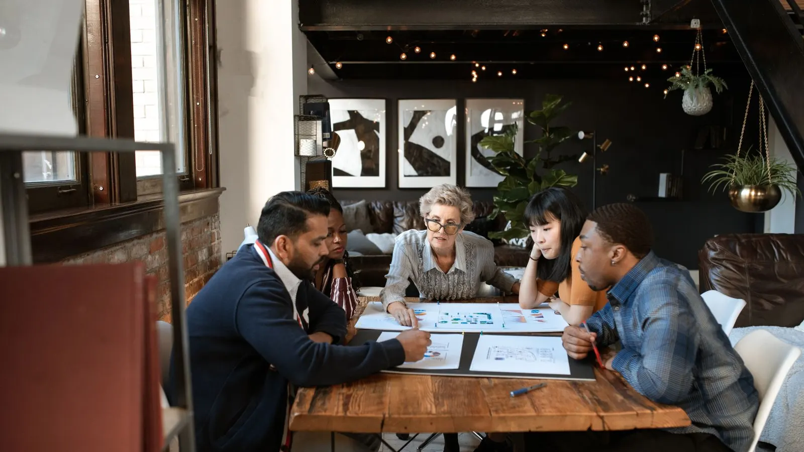 Colleagues reviewing documents and a laptop around a wooden table.