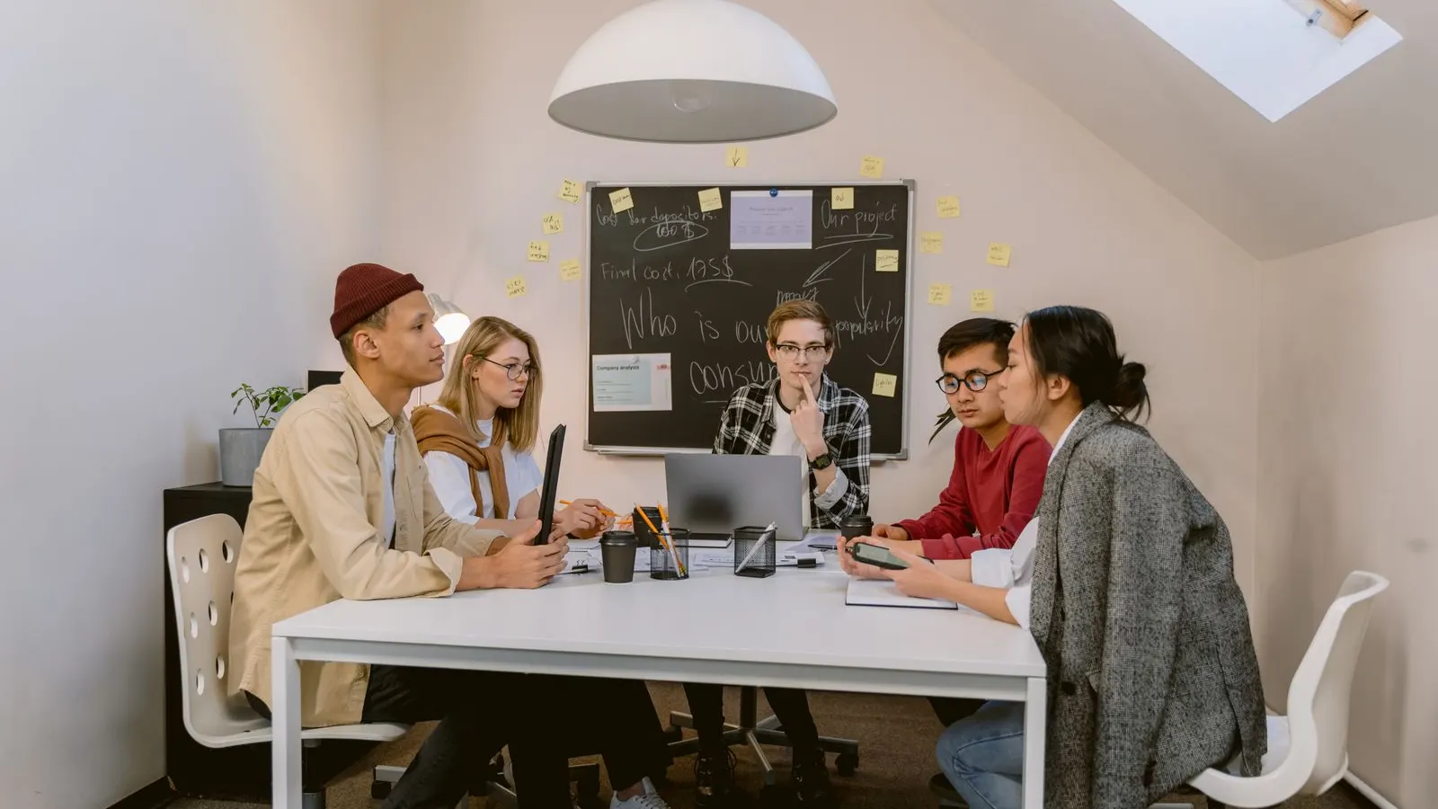 Colleagues talking together around a laptop at a white office table.