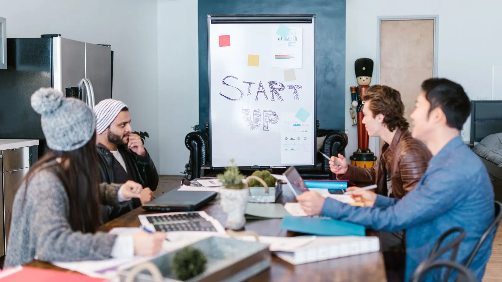 A team discussing ideas around a laptop with a planning board behind them.
