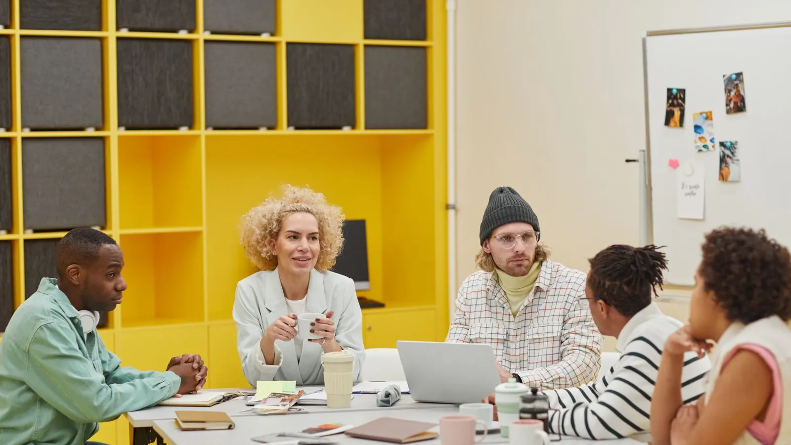 Colleagues discussing papers together in a bright office with yellow shelving.