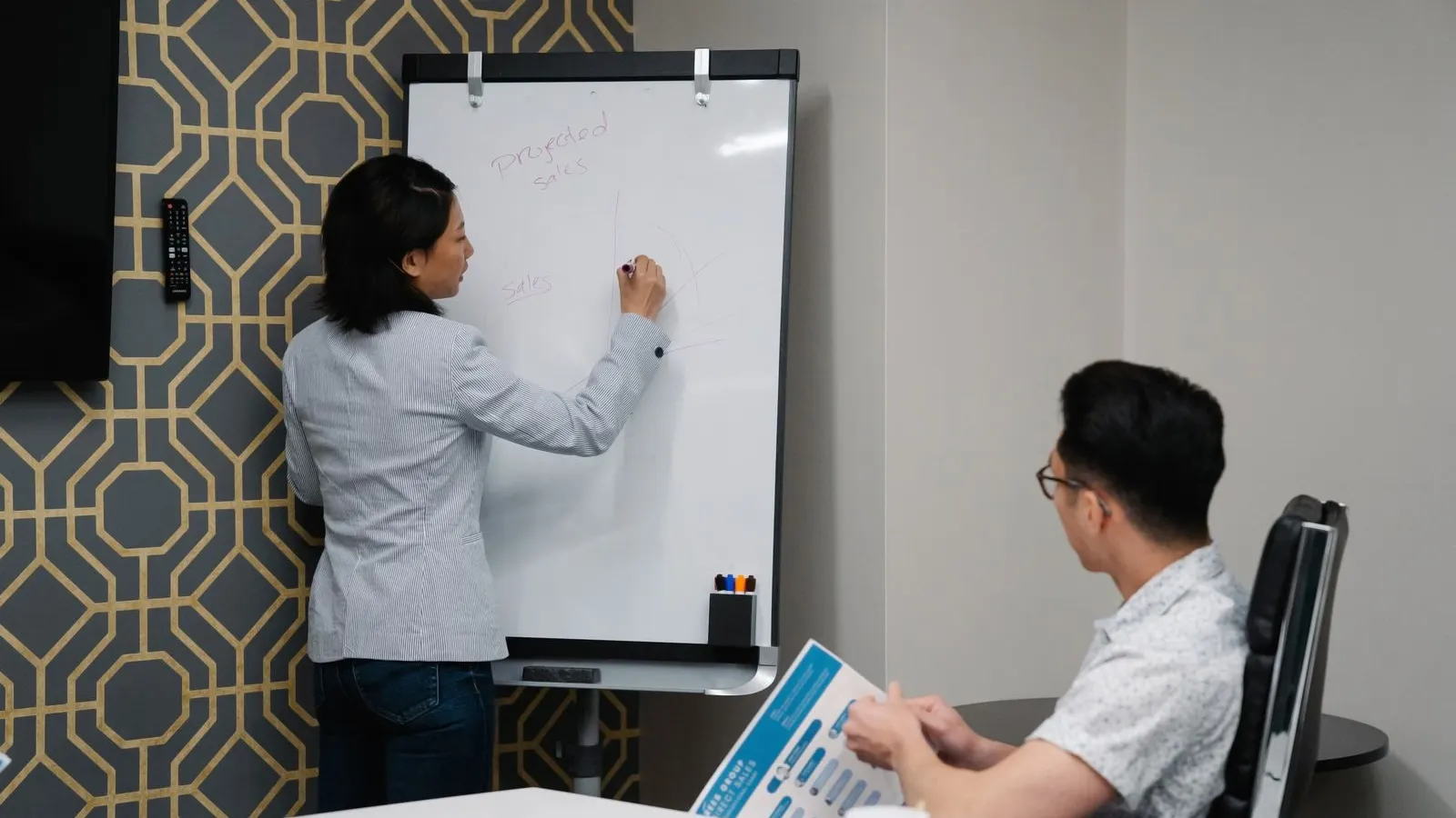 Colleagues discussing notes and a whiteboard during a planning session.