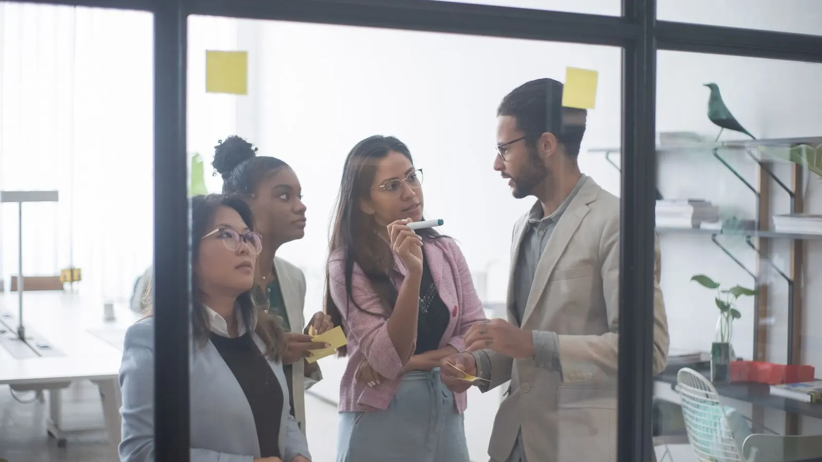 Colleagues gathering around a laptop during a collaborative office discussion.